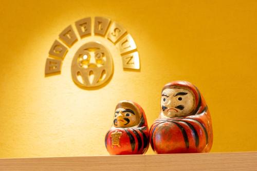 two wooden statues sitting on a shelf with a clock at Hotel Sun in Takasaki