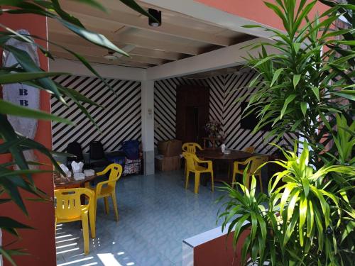 a restaurant with yellow chairs and tables and plants at Dhonveli Hotel in Shaviyani Atoll