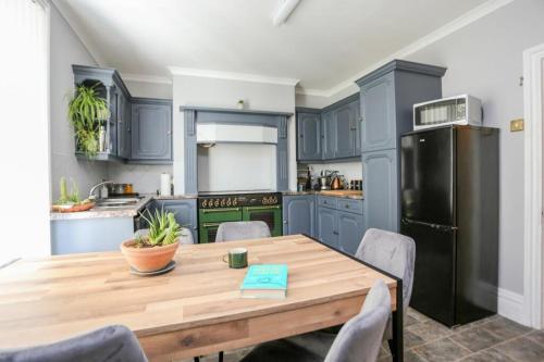 cocina con mesa de madera y nevera negra en Southsea Historic Gem - Elegant Apartments, en Portsmouth