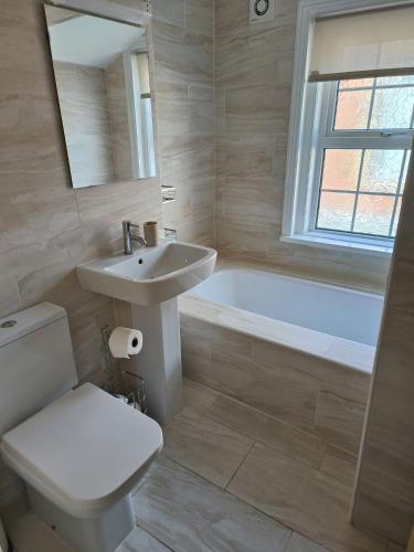 a bathroom with a sink and a toilet and a tub at Southsea Historic Gem - Elegant Apartments in Portsmouth