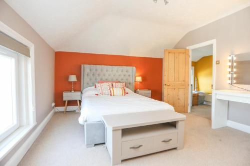 a bedroom with a bed with an orange wall at Southsea Historic Gem - Elegant Apartments in Portsmouth
