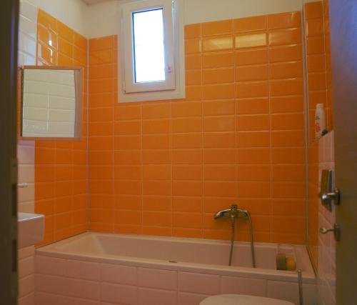 an orange tiled bathroom with a tub and a toilet at Villa Katafyki (2 independent houses) in Ermioni