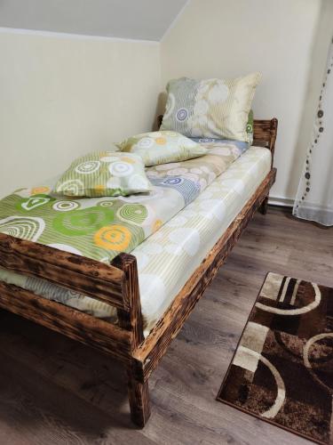 Cama de madera en habitación con alfombra en Casa din livadă - Cazare Măgheruș en Topliţa