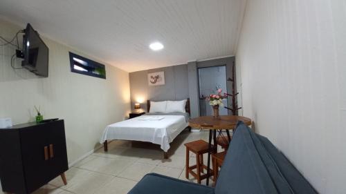 Schlafzimmer mit einem Bett, einem Tisch und einem TV in der Unterkunft Suíte Aconchegante em Hospedaria no Centro in Ouro Preto