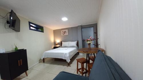 a bedroom with a bed and a table and a tv at Suíte Aconchegante em Hospedaria no Centro in Ouro Preto