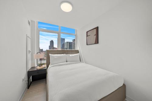 a white bedroom with a bed and a window at Level Chicago - Fulton Market in Chicago