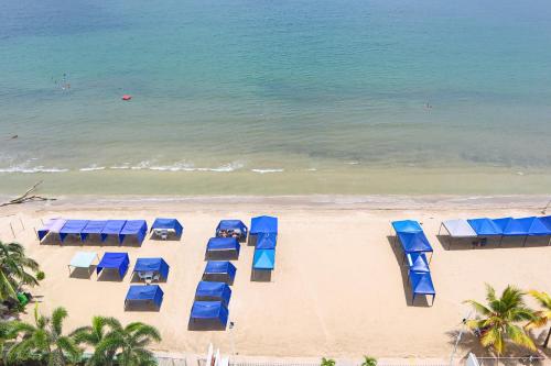 einen Blick über den Strand mit blauen Sonnenschirmen in der Unterkunft Mágico Apartamento Frente al Mar 3 Habitaciones PV82 in Coveñas