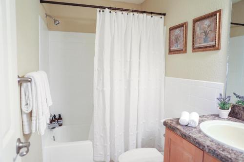 拉哥的住宿－Sunnyside Palms - 2BR, Poolside, 5 min to Beach，浴室设有白色的淋浴帘和水槽