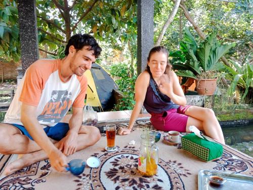 Gerung的住宿－Gecko Tropical inn，坐在桌子旁的男人和女人