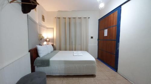 a small bedroom with a bed and a wooden door at Suíte Charmosa em Hospedaria no Centro in Ouro Preto