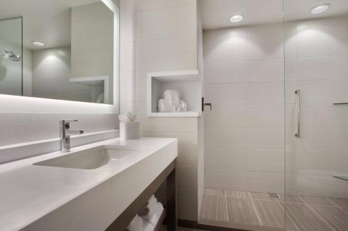 a white bathroom with a sink and a shower at Courtyard by Marriott Orlando South/Grande Lakes Area in Orlando