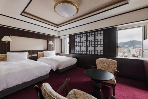 Habitación de hotel con 2 camas, mesa y sillas en Richmond Hotel Nagasaki Shianbashi, en Nagasaki