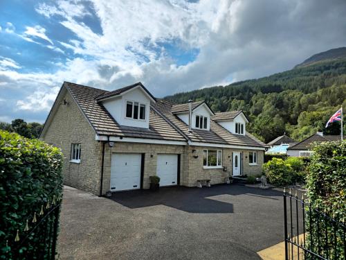 a house with two garage doors and a mountain at Gleann Fia House in Arrochar