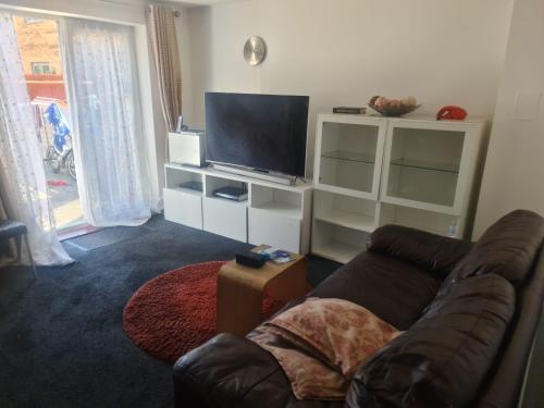 uma sala de estar com um sofá e uma televisão de ecrã plano em D Merciful Homes em Kent