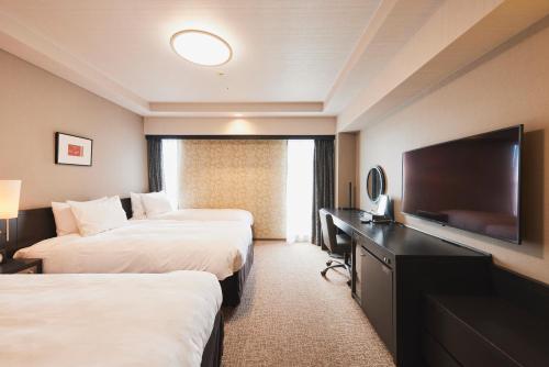 a hotel room with two beds and a flat screen tv at Richmond Hotel Nagasaki Shianbashi in Nagasaki