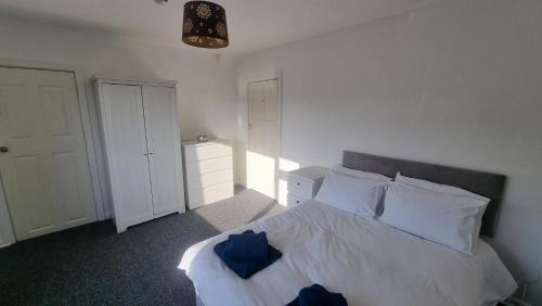 um quarto com uma cama com lençóis brancos e almofadas azuis em Flat in Nottingham em Nottingham