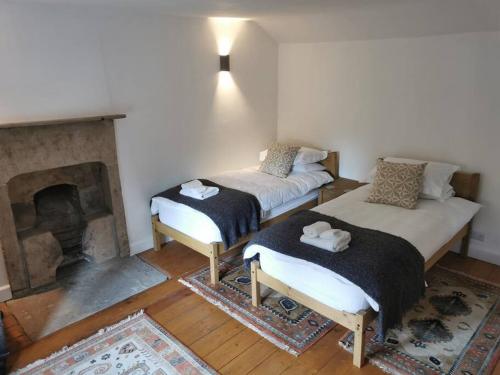 two beds in a room with a fireplace at Bridgefoot Cottage in Froggatt