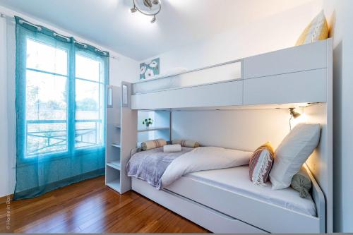 a white bedroom with a bunk bed and a window at Gîte La Villa Omagny Paris Marne-la-Vallée in Magny-le-Hongre