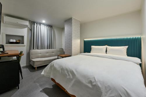 ソウルにあるHotel Chloeの大きな白いベッドとソファのある寝室