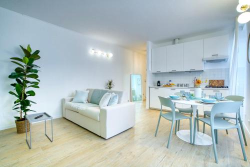 een woonkamer met een witte bank en een tafel en stoelen bij Leafy Sunshine, Bilocale in Porta Venezia, con Metro a 1 min a piedi in Milaan