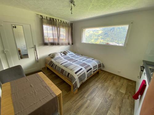 a bedroom with a bed and a window and a table at Aux Grands-Vergers in Bruson