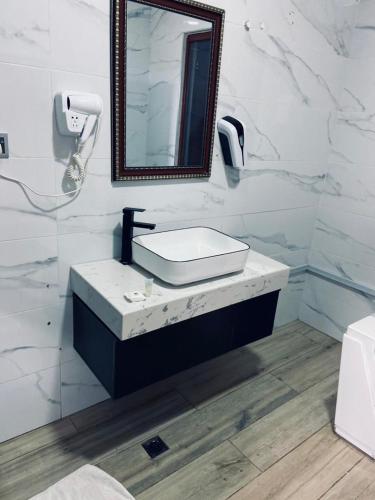 a white bathroom with a sink and a mirror at Dellagio Hotel in Wa