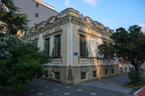 a large white building with trees in front of it at Karvi Hostel & Suites in Batumi