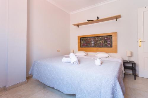 Un dormitorio con una cama blanca con toallas. en Piso Velero Cerca a la Playa Sanlucar de Barrameda, en Sanlúcar de Barrameda