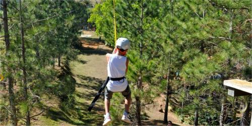a man on a zip line in the trees at HOTEL FAZENDA ROCHEDO in Conservatória