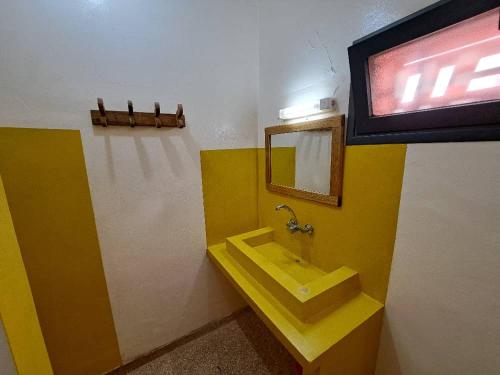 uma casa de banho com um lavatório amarelo e um espelho. em Le Kenkeni em Ouoran
