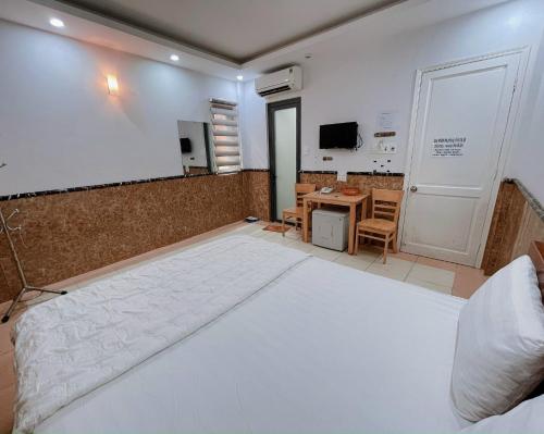 a bedroom with a large white bed and a table at Hoài Thu Hotel Vũng Tàu in Vung Tau