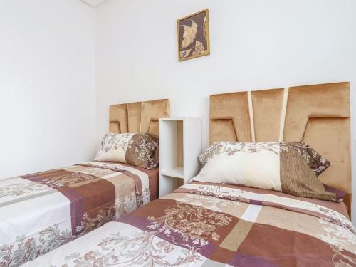 a bedroom with two beds and a picture on the wall at Magnifique Appartement Golf Tanger for Families in Tangier