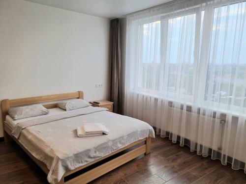 - une chambre avec un lit et une grande fenêtre dans l'établissement Apart Panorama, à Lviv