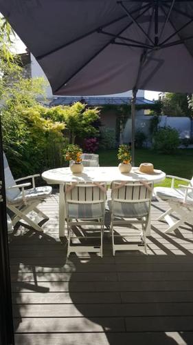 une table et des chaises blanches sous un parasol dans l'établissement Chez Lily, à Vélizy-Villacoublay