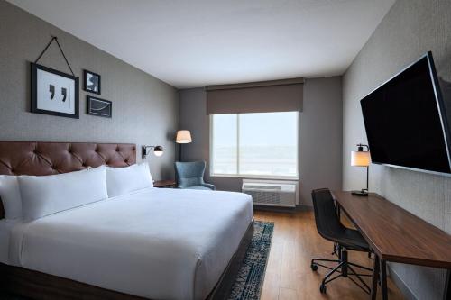 Habitación de hotel con cama, escritorio y TV. en Four Points by Sheraton Fort Worth North, en Fort Worth