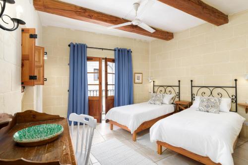 a bedroom with two beds and a table at Dar ta' Lonza Villa with Private Pool in Għasri
