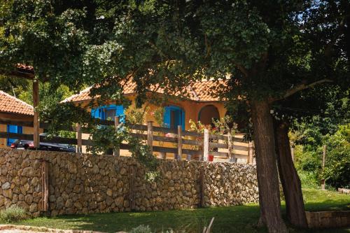 ein Haus hinter einem Steinzaun mit einem Baum in der Unterkunft Zeleni zaliv-The Green Bay in Donji Milanovac
