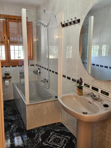 Un baño con lavabo, bañera y espejo. en Cortijo Los Portillos, en Arbuniel