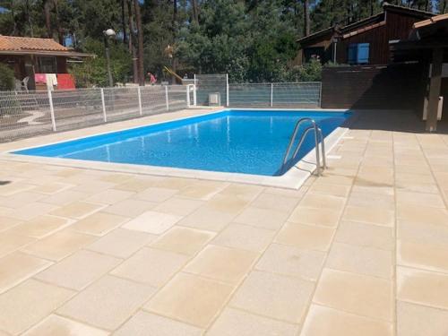 a swimming pool with blue water in a yard at CHALET avec PISCINE proche LAC et OCEAN in Carcans