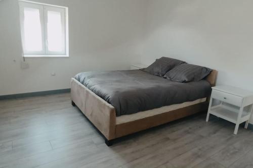 Grand appartement lumineux. في Denain: سرير في غرفة بيضاء مع كومودينو وسرير سيد