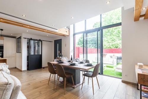 une salle à manger et un salon avec une table et des chaises dans l'établissement Charmante Maison Climatisée avec son Jardin à 10 minutes de DIJON, à Marsannay-la-Côte