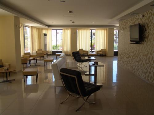 een wachtkamer met stoelen en tafels en een tv bij Merope Hotel in Karlovasi