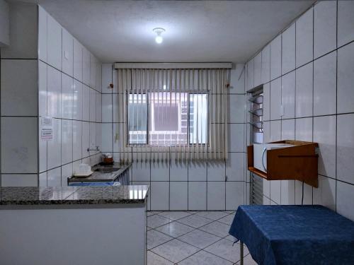uma cozinha com paredes de azulejos brancos e uma janela em Pousada Guarulhos em Guarulhos