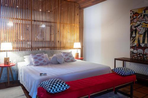 a bedroom with a large white bed with a red bench at Hotel Villaggio Tudo Bom in Uruau