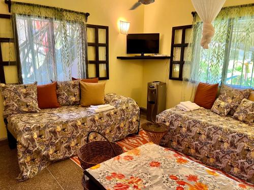 sala de estar con 2 sofás y TV en Private cottages @ Karibuni Villas en Malindi