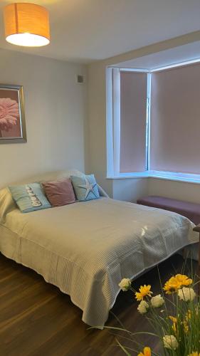 a bedroom with a bed with a window and flowers at Bexhill Beautiful Sea Front Bungalow in Bexhill