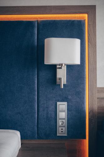 a lamp on a blue wall next to a bed at Hotel Unitral SPA w Mielnie in Mielno