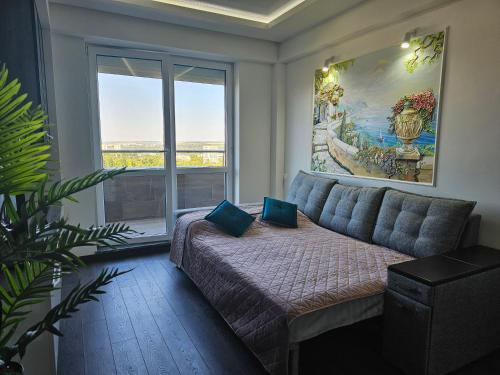 a living room with a couch and a large window at Apartment Dendrarium Residence in Chişinău