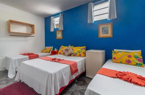 a room with two beds and a blue wall at Magia D'ajuda Hospedagem in Arraial d'Ajuda