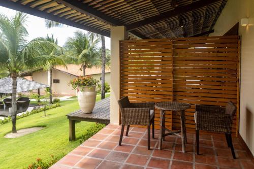 a patio with a wooden fence and a table and chairs at Hotel Villaggio Tudo Bom in Uruau
